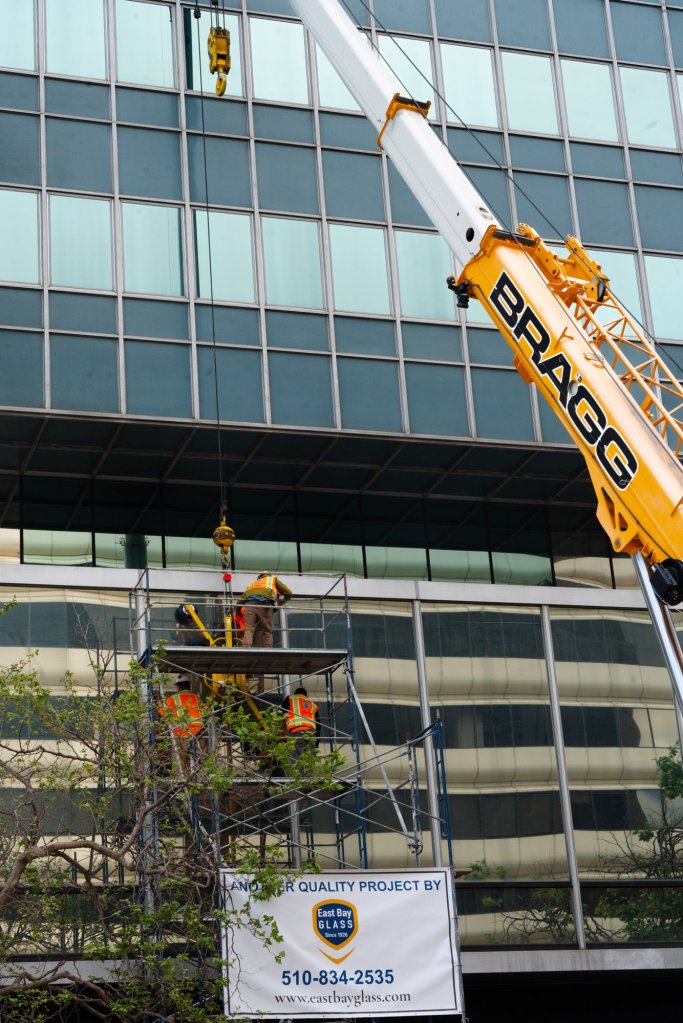 Crane lifting glass for an East Bay Glass curtain wall replacement project on Broadway in downtown Oakland