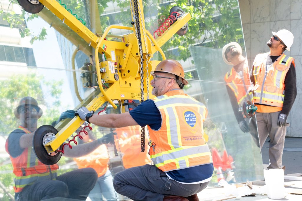 East Bay Glass team rigging a large glass panel with a quad-cup vacuum lifter before a crane lift in Oakland